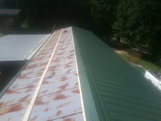 Old rusted panels beside newly installed green metal roofing — Wind Damage Roof Repair by Roofing Brothers in Floral