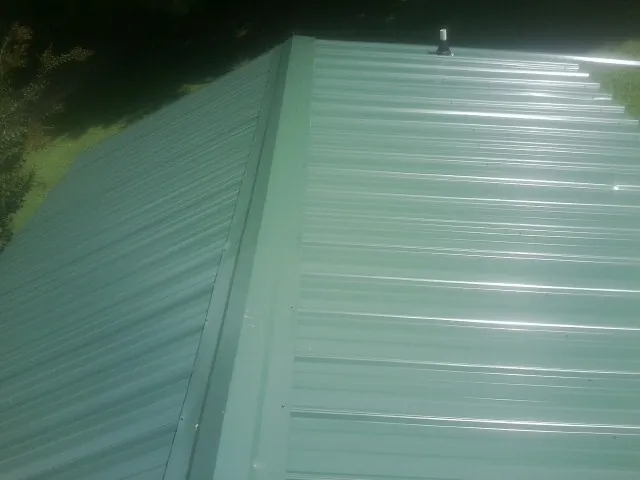 New green metal panels meeting at the ridge of a roof — Flat Roof Repair work by our crew in Floral