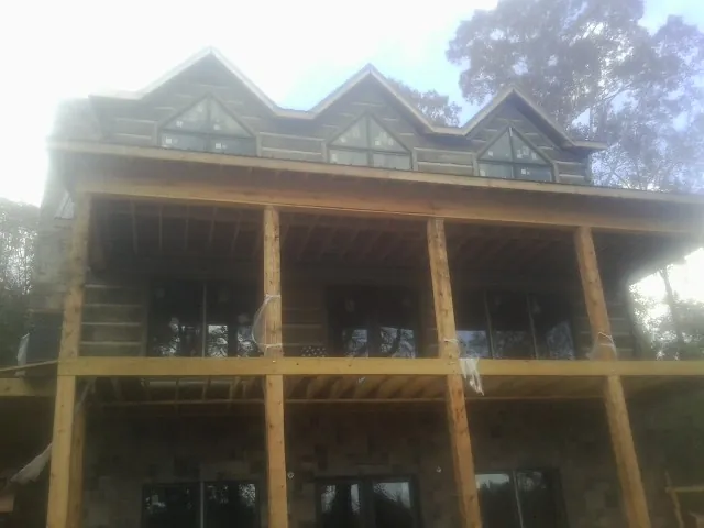 Dormers and porch framing on a large log home under construction — Roof Coating work by our crew in Floral