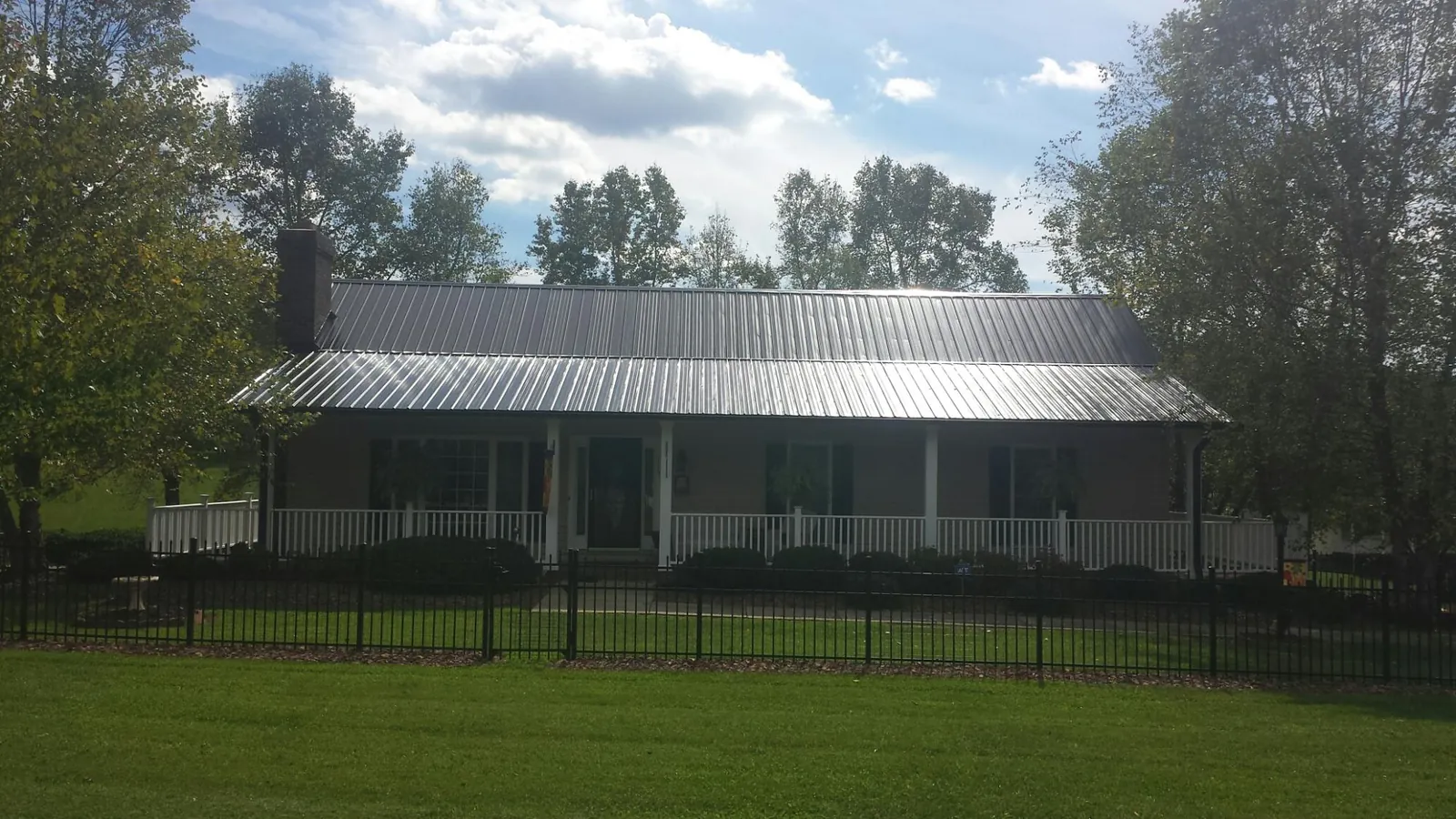 Gray metal roof on a brick ranch with a full width front porch — Gutter Guard Installation work by our crew in Floral