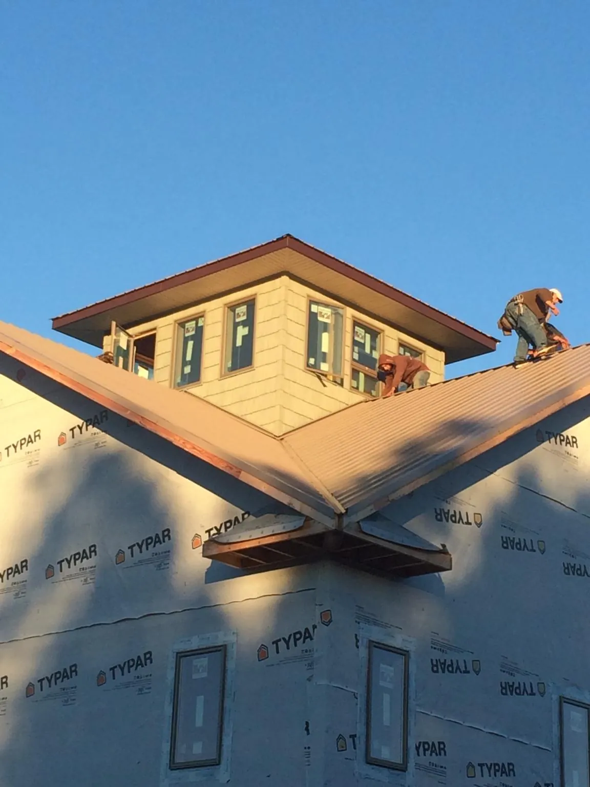 Roofers working around a rooftop cupola on a new metal roof at sunset — Roof Waterproofing in Floral by Roofing Brothers